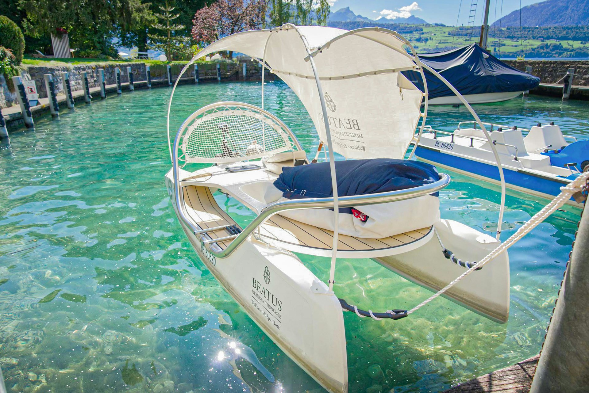A small catamaran with a sun sail moored in a harbour