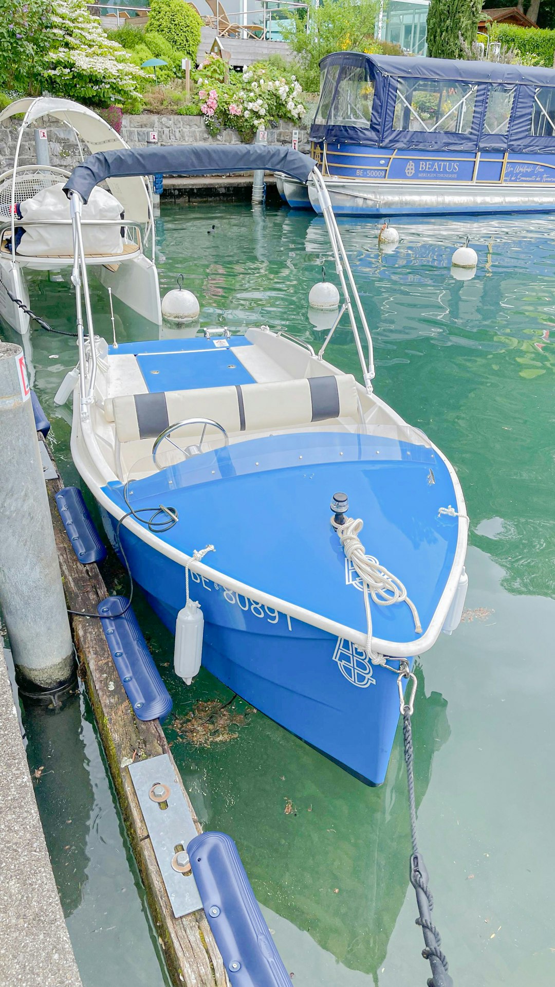 Ein kleines Boot liegt am Hafen, dahinter ein Ausflugsboot