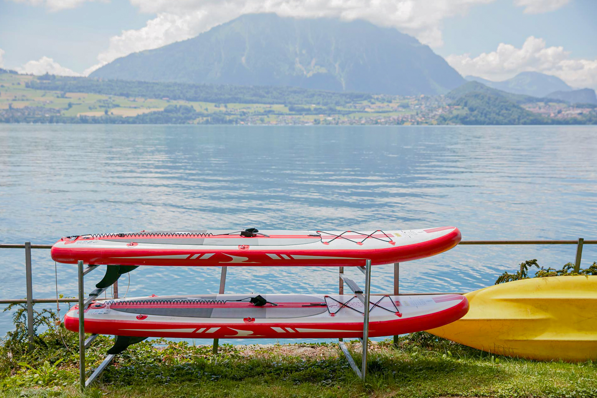 Two red SUPs in front of Lake Thun, with a large mountain behind them