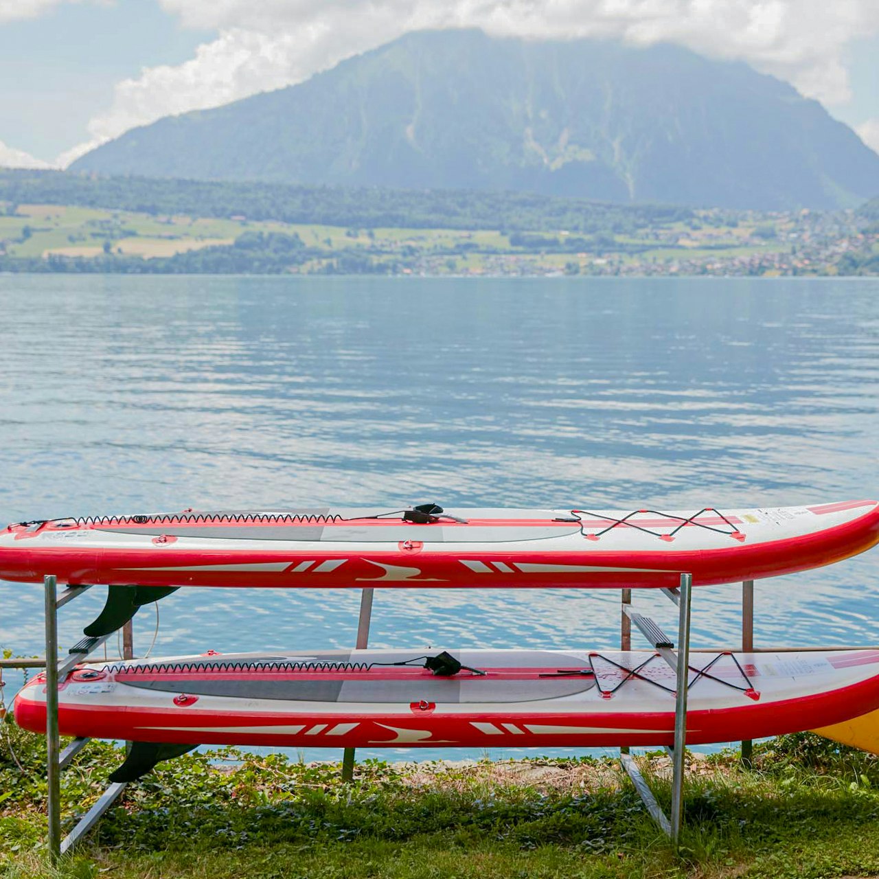 Wassersport im Hotel BEATUS Zwei rote SUP liegen vor dem Thunersee, dahinter ein grosser Berg
