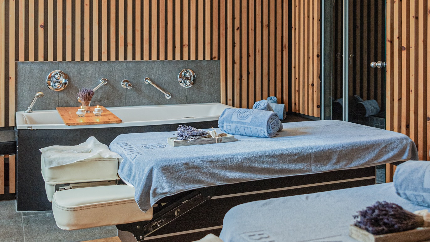 Massage im Hotel BEATUS Zwei Massageliegen mit Badetüchern in einem Raum mit Holzlatten vor den Wänden