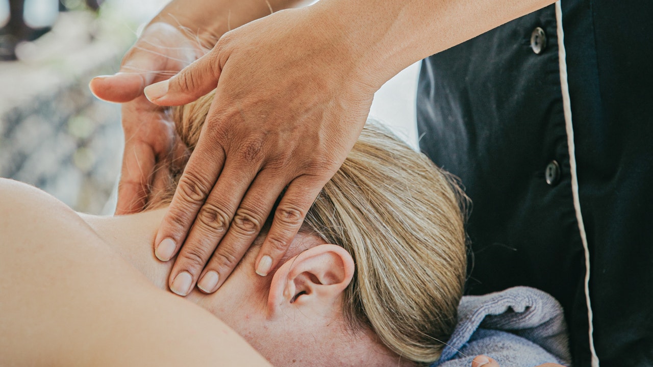 Massage au bord du lac à l'hôtel BEATUS Une femme est allongée sur le ventre, sa nuque est massée, derrière elle, le lac.
