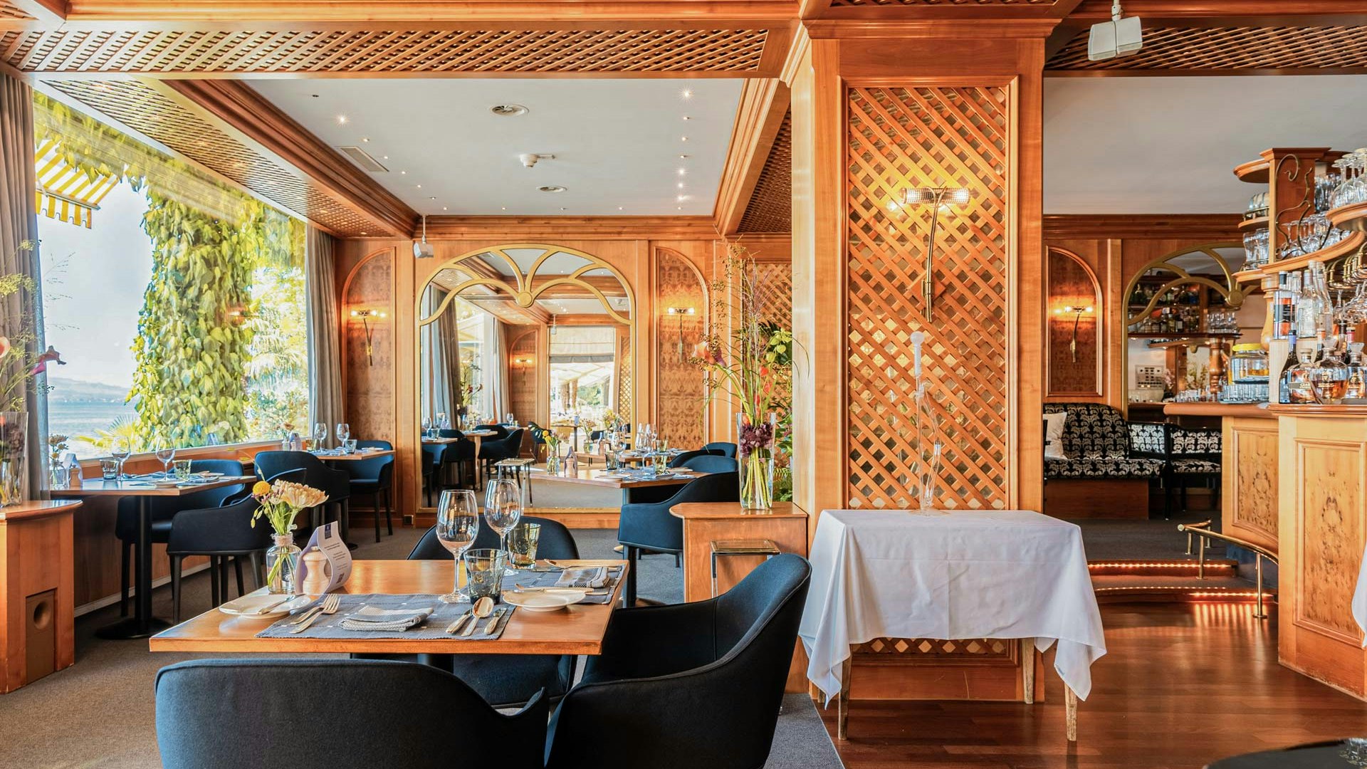 Die Orangerie im Hotel BEATUS Schwarze gepolsterte Stühle, gedeckte Tische, dahinter eine honigbraune Holzverkleidung