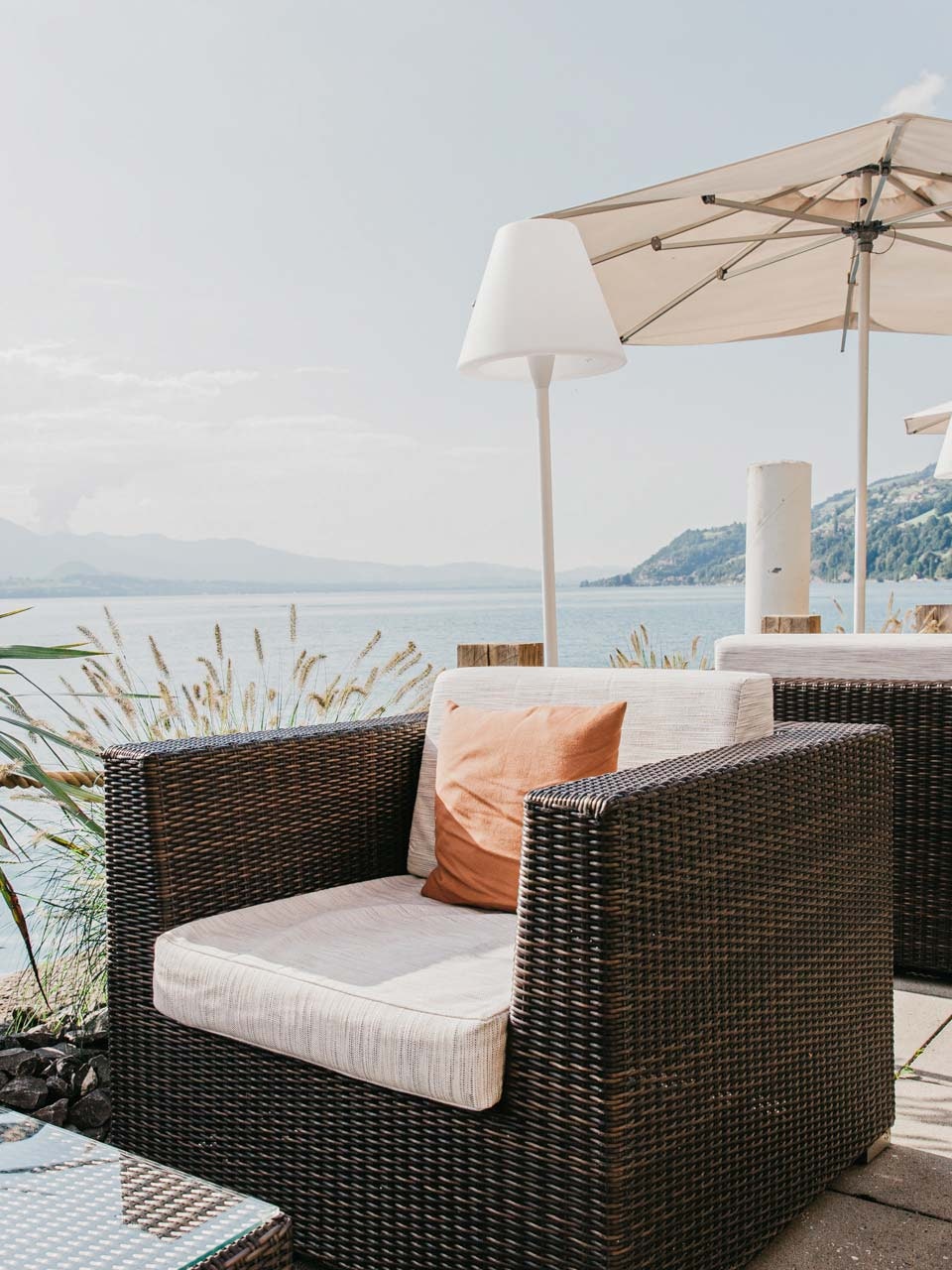 SeeLounge at the Hotel BEATUS Lounge furniture, parasols and floor lamps on a terrace, with the lake to the left