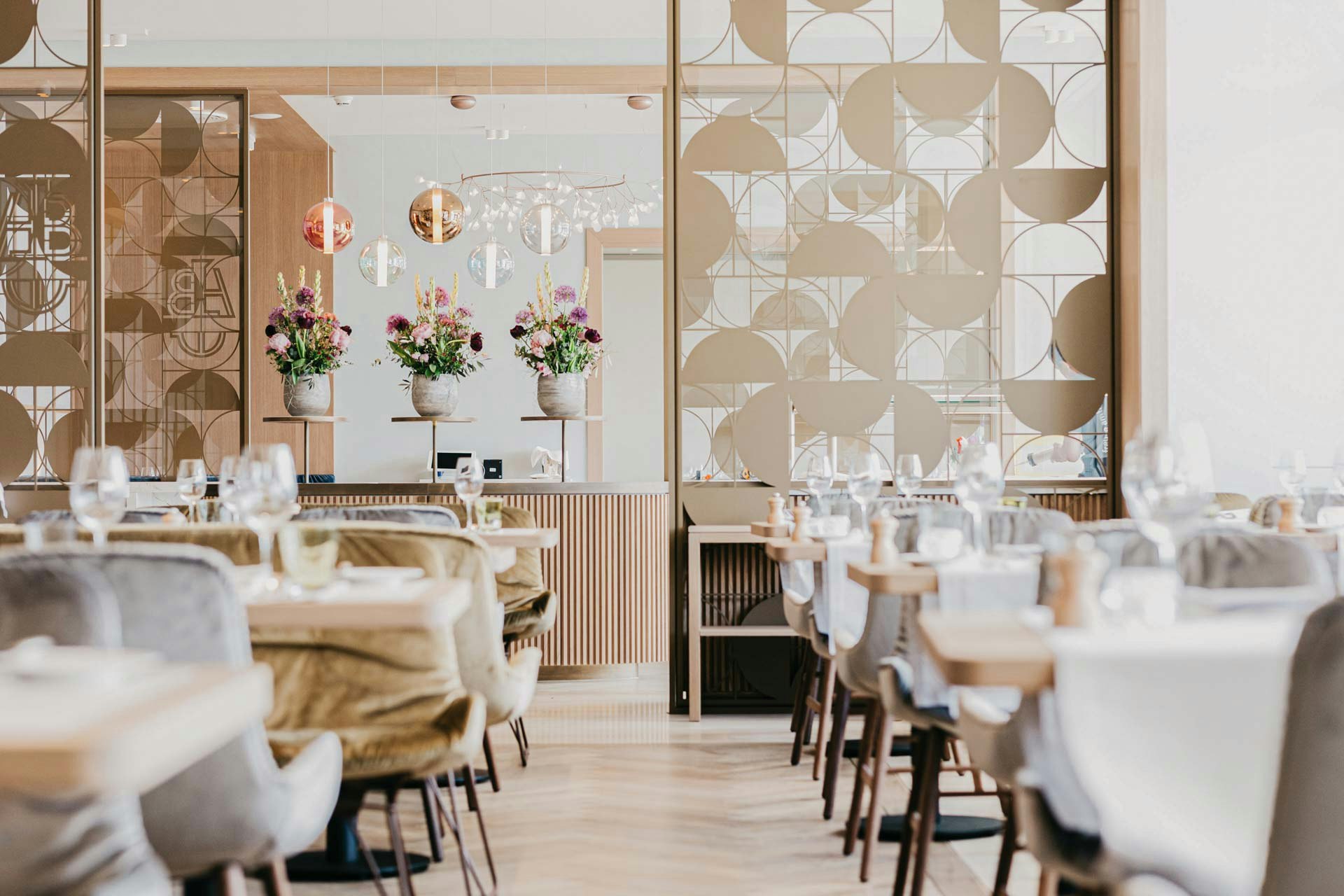 Chairs covered with velvet, behind them an artistic partition made of golden metal, flowers