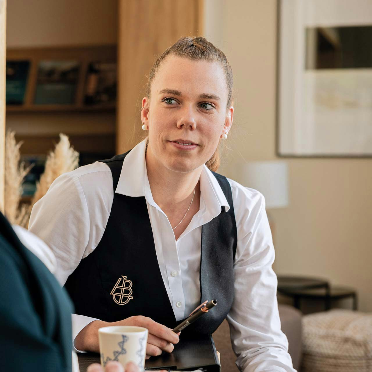 Martina Kohli at work in the Hotel BEATUS Friendly woman with white shirt and black gilet in customer contact