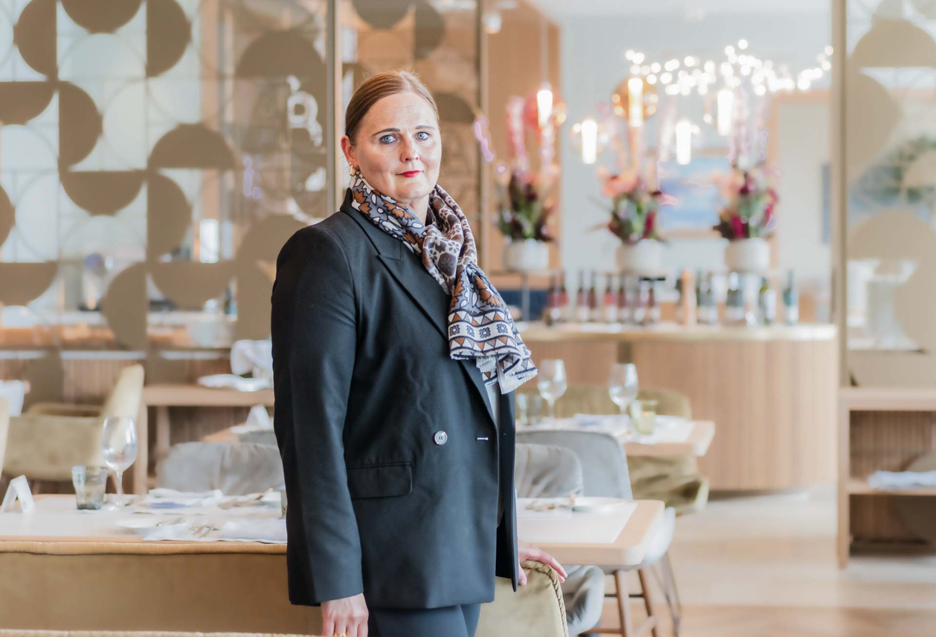 Frau im schwarzen Sakko mit buntem Schal in einem Restaurant