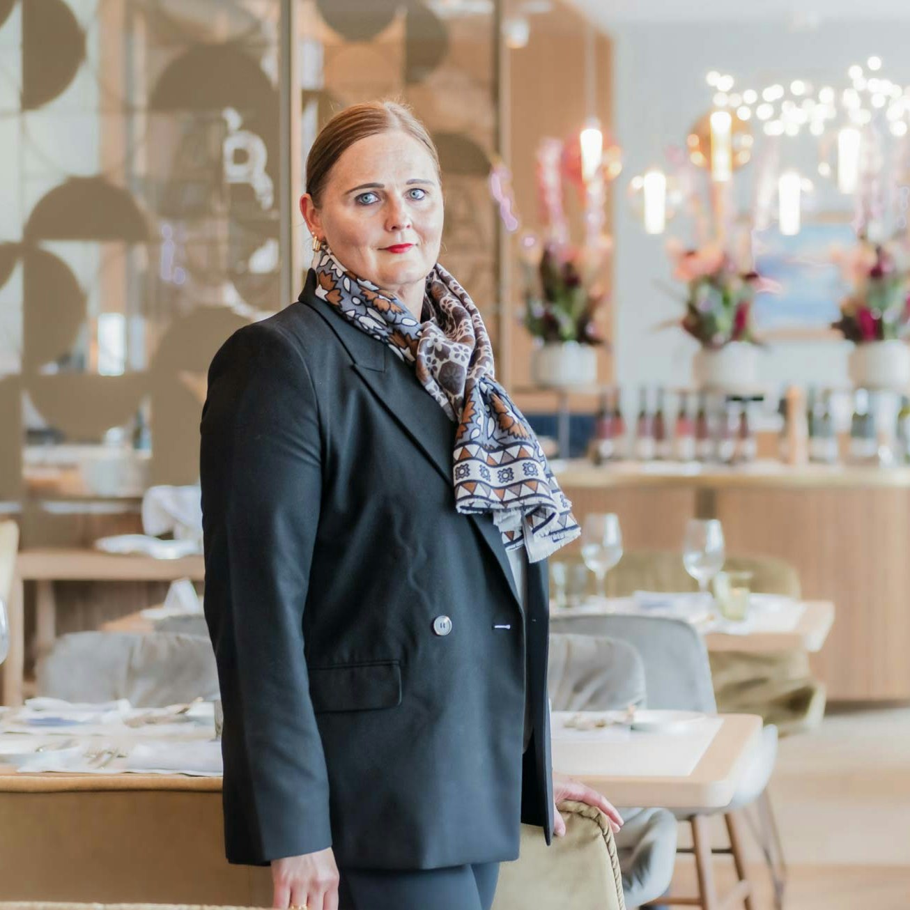 Susanne Luginbühl, Vice Director Rooms at Hotel BEATUS Woman in a black jacket with a colourful scarf in a restaurant