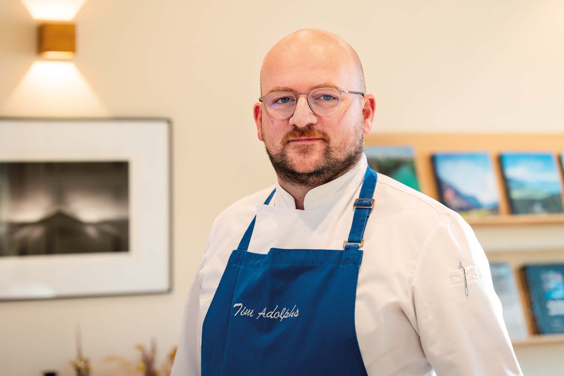 Bärtiger Mann mit Brille, weissem Hemd und blauer Schürze