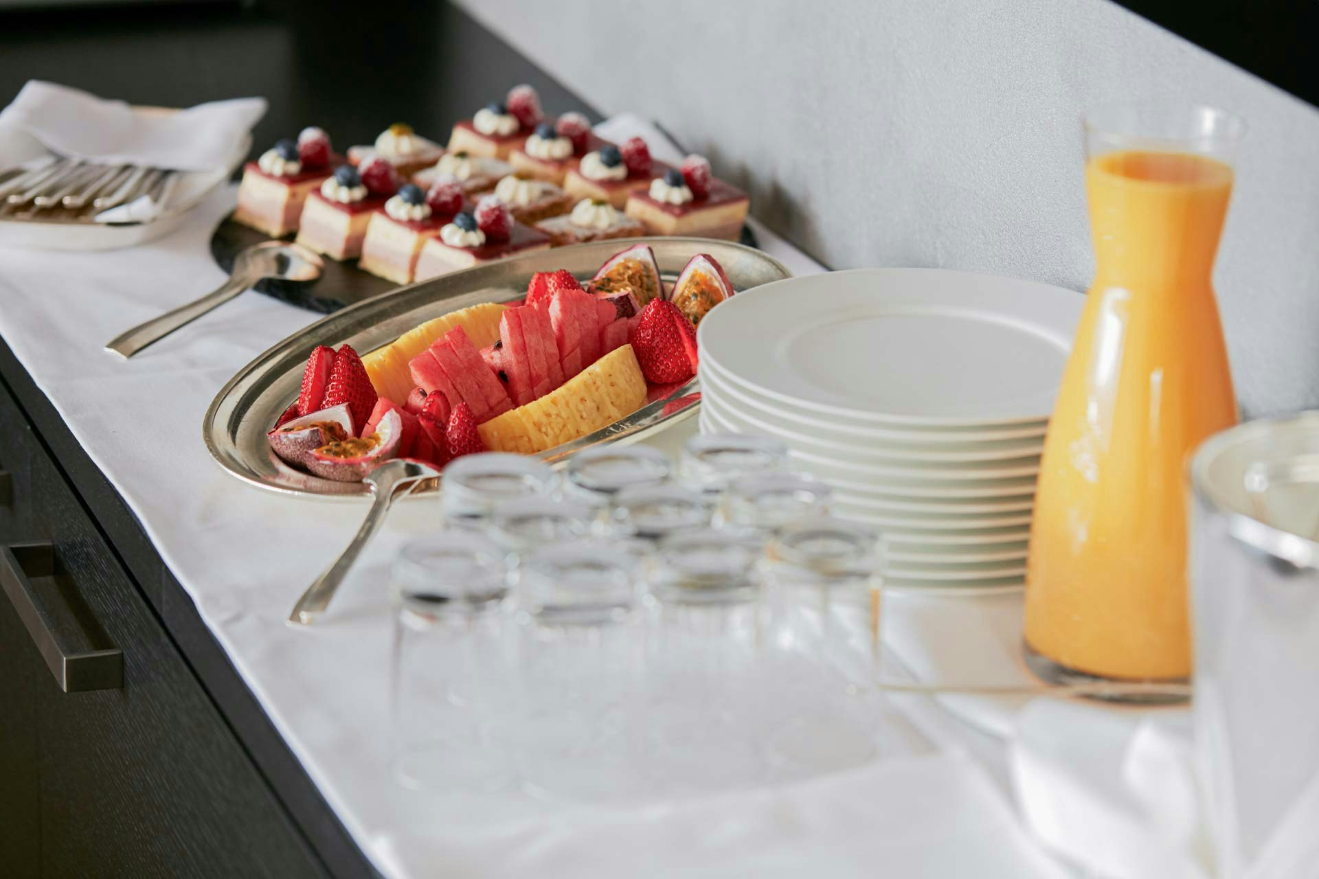 Assiettes, verres, jus de fruits, fruits rouges et jaunes, petits desserts