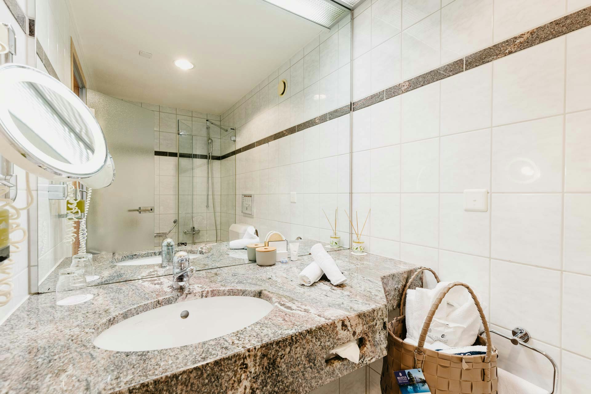 Salle de bain avec lavabo, grand miroir, miroir de maquillage et sac de bain