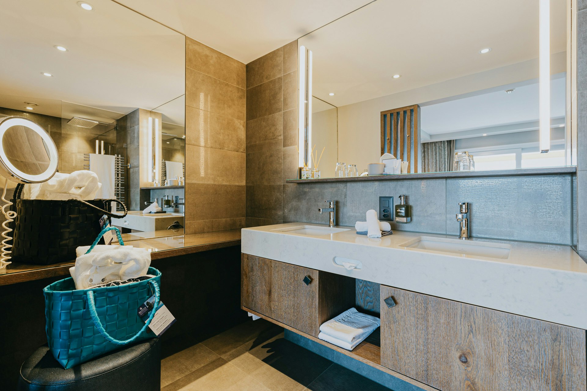 Badezimmer mit Kosmetikspiegel, Badetasche, zwei eingebauten Waschbecken und Spiegel