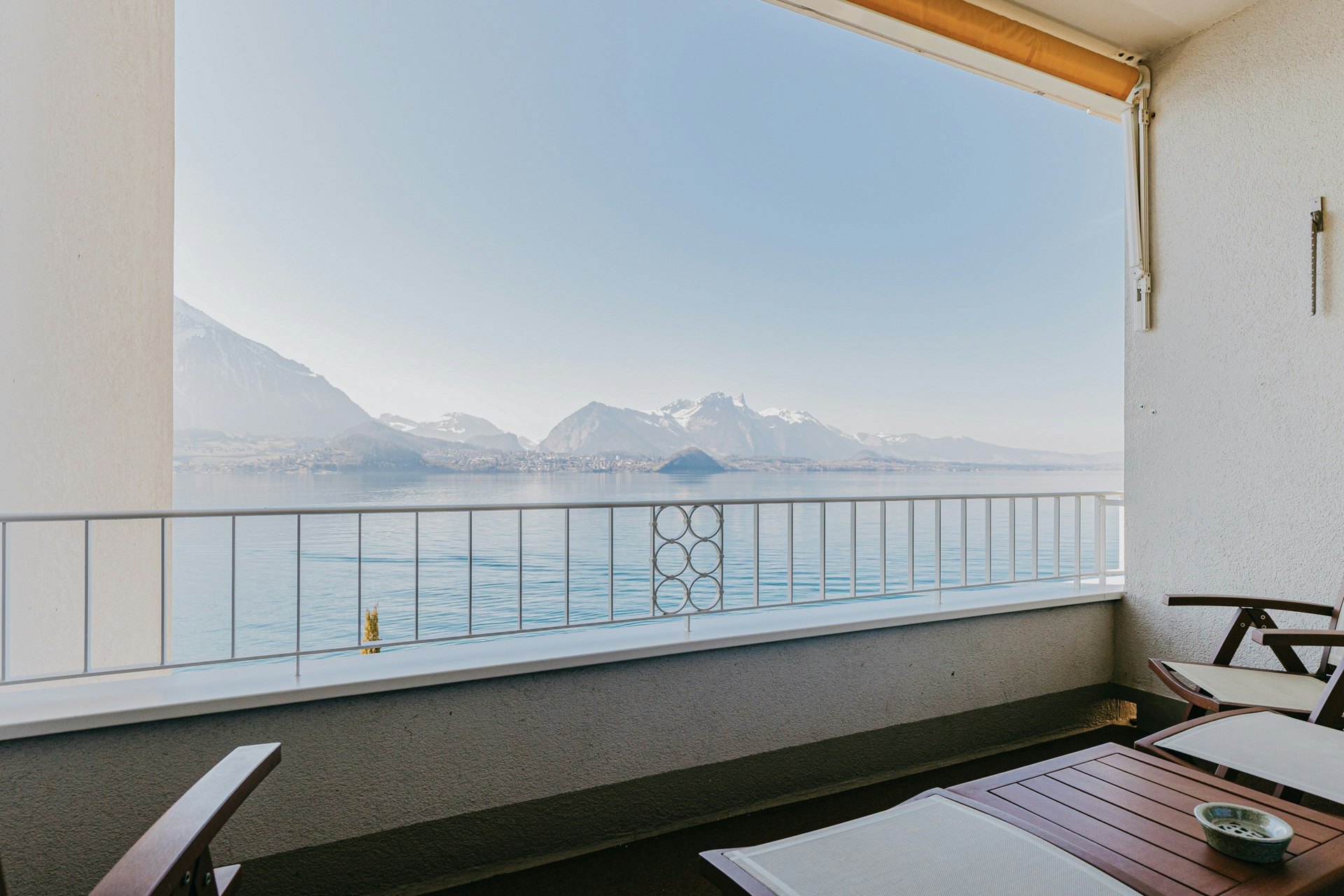 Balcon avec chaises et table, au centre la vue sur le lac et les montagnes