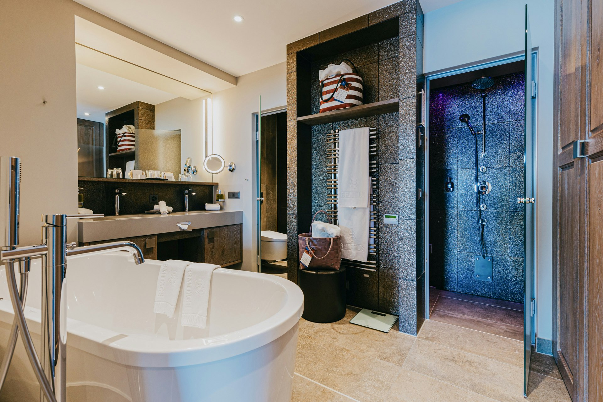 Salle de bain avec une baignoire à l'avant, une douche à l'arrière et entre les deux un lavabo et un grand miroir