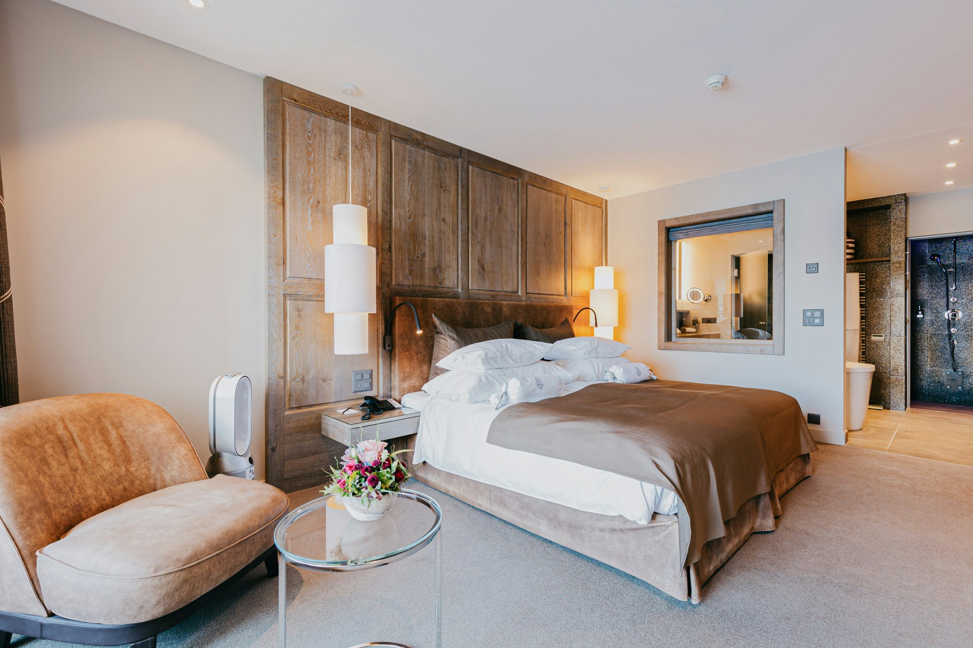 Vue d'une chambre à coucher avec un lit double, des lampes suspendues et un meuble rembourré au premier plan