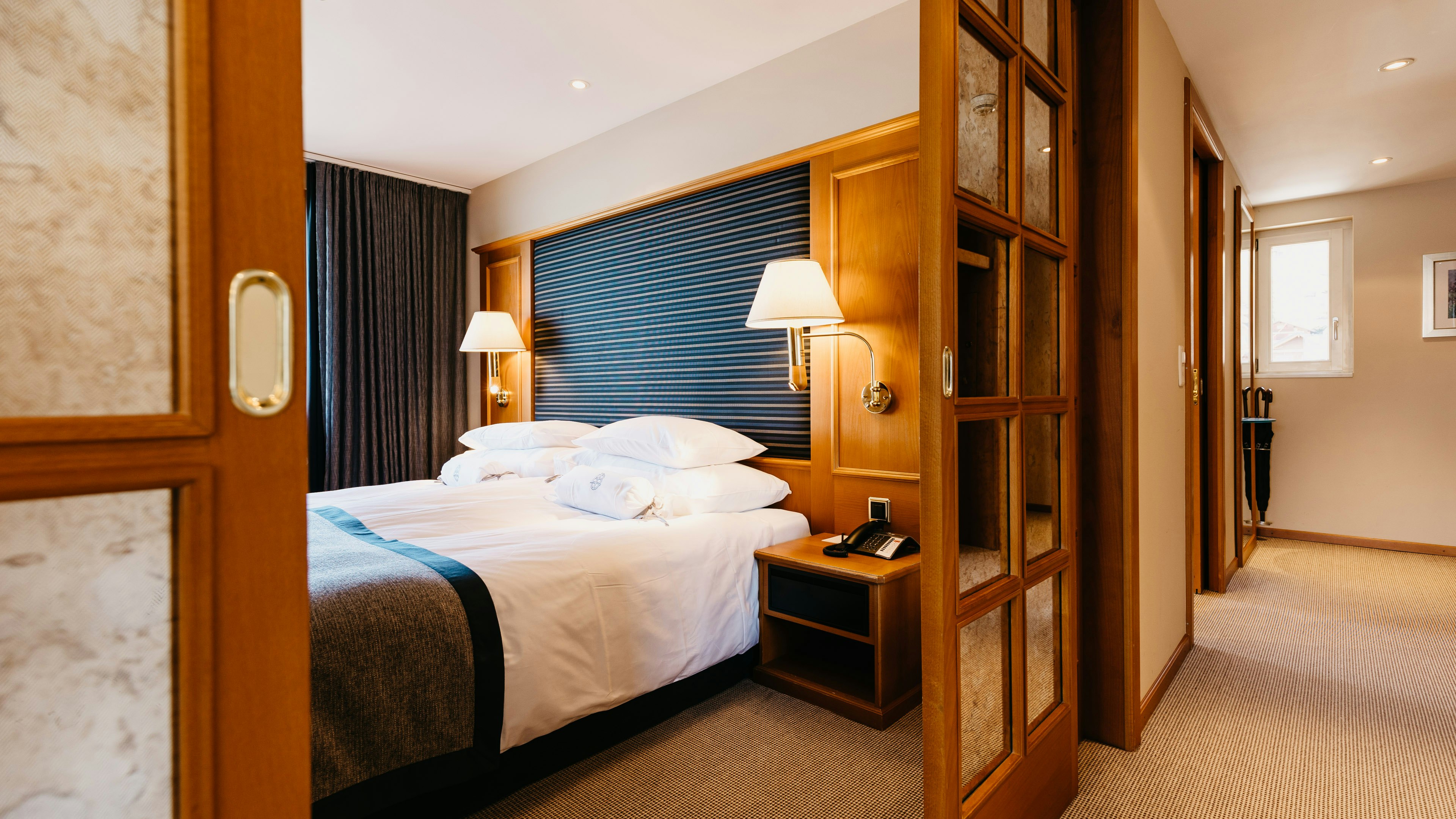 Wellness suite at the Hotel BEATUS View from the corridor through an open sliding door to a double bed and wall lamps