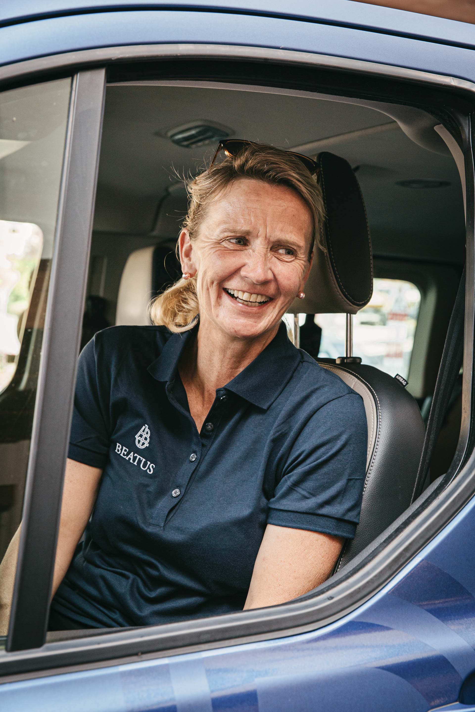 Une femme joyeuse est assise dans une voiture à l'arrêt avec la fenêtre ouverte