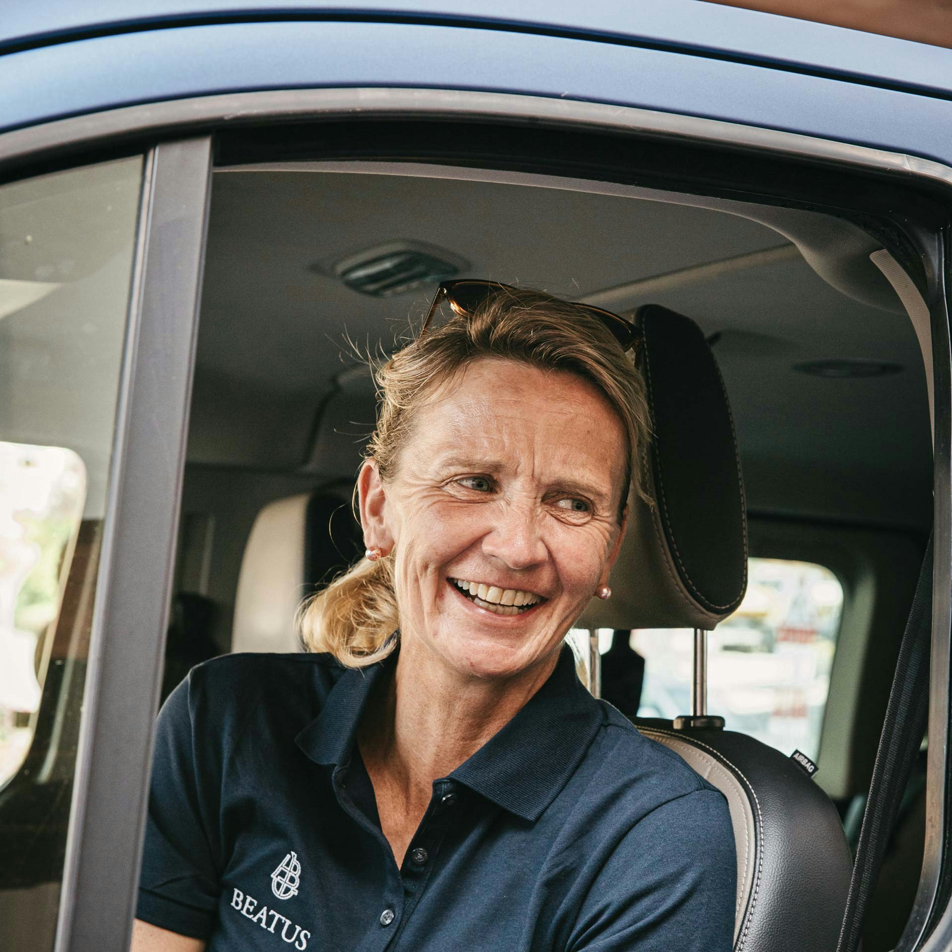 Susanne Fahrni is a nature guide at the Hotel BEATUS A cheerful woman sits in a stationary car with the window open
