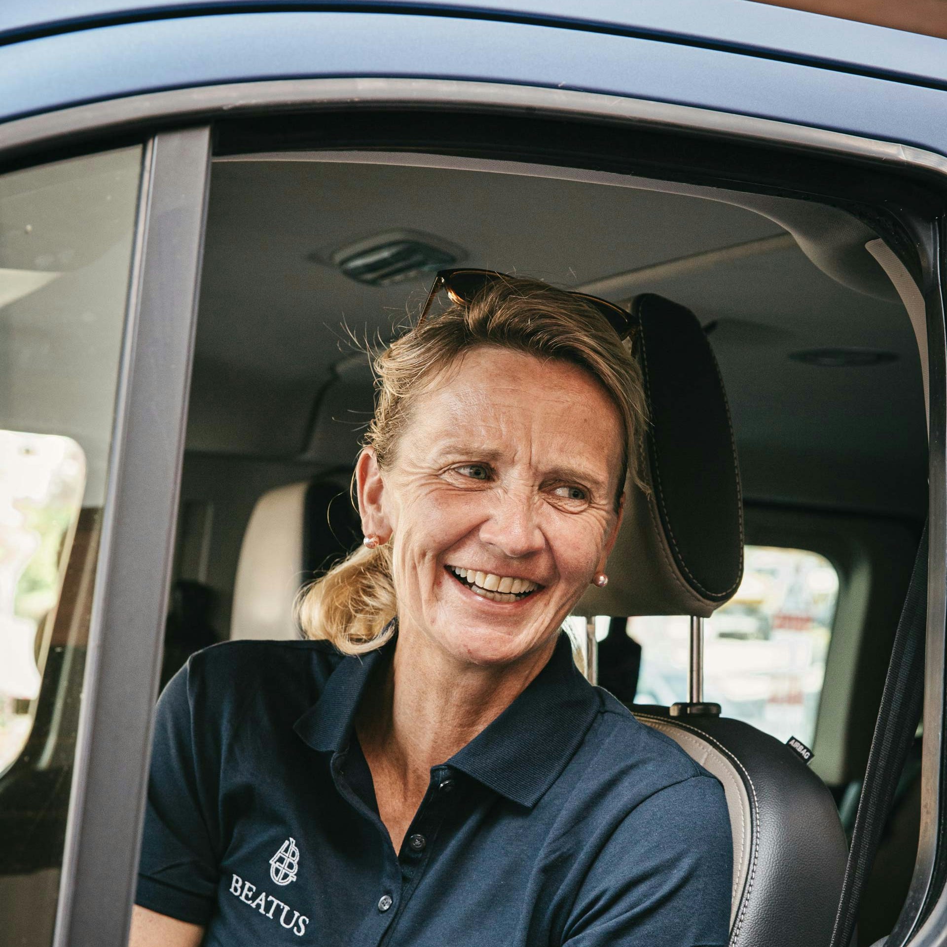 Susanne Fahrni est guide nature à l'hôtel BEATUS Une femme joyeuse est assise dans une voiture à l'arrêt avec la fenêtre ouverte