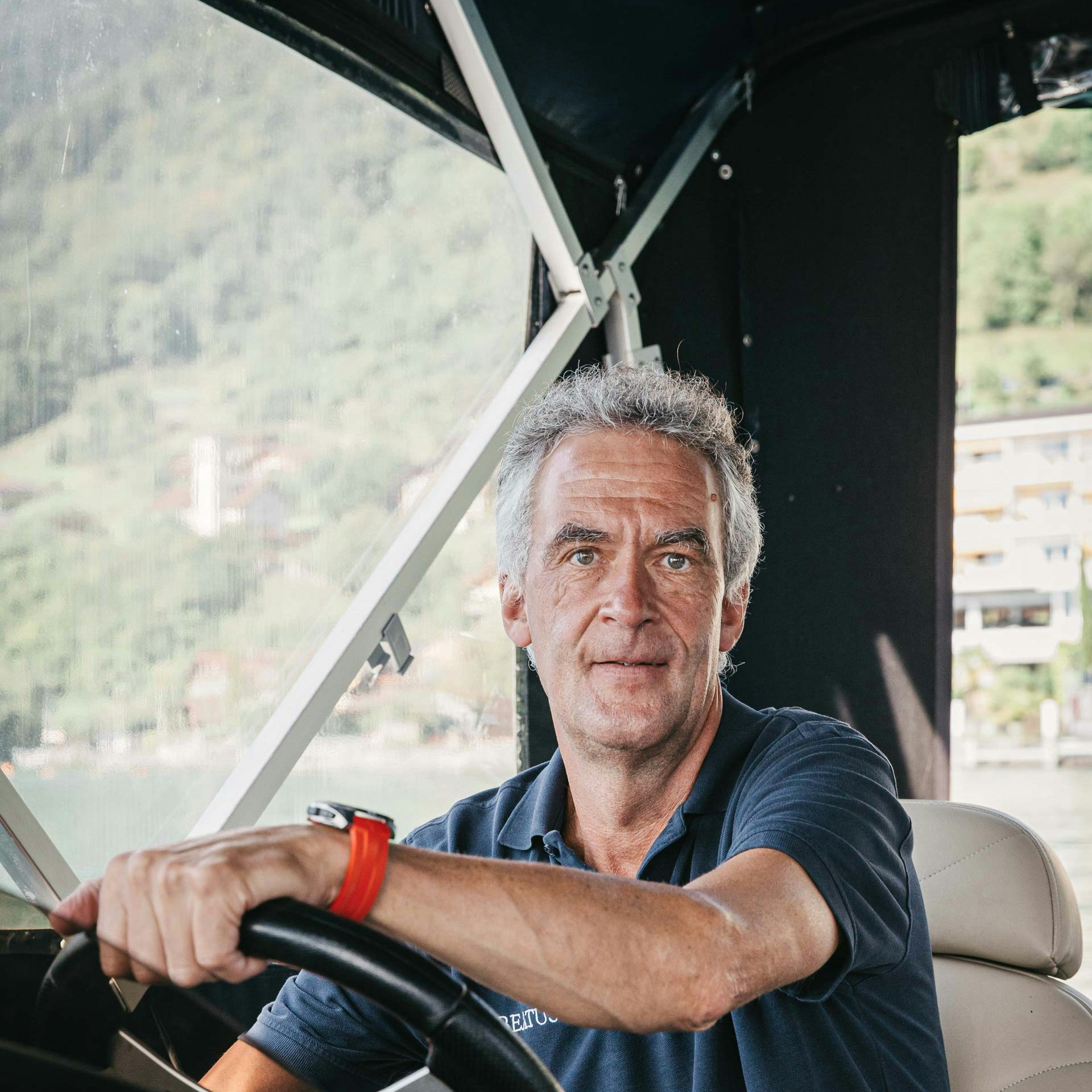 Volker Dietl ist Natur-Guide im Hotel BEATUS Ein Mann schaut direkt in die Kamera, seine Hände liegen auf dem Steuerrad eines überdachten Bootes