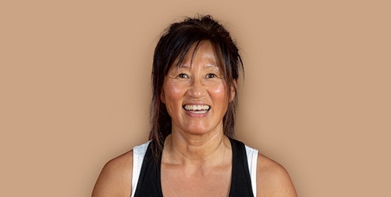 Jenny Weibull, yoga teacher at Hotel BEATUS Laughing tanned woman, cropped against a brown background