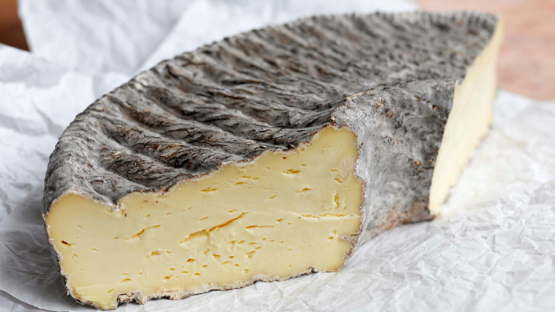 Cheese from the Städtlichäsi Lichtensteig Large piece of cheese with dark furrowed skin on white paper