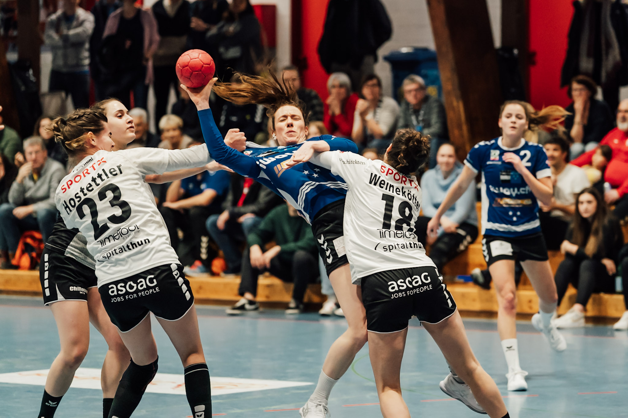 Three female handball players dispute the ball with a woman from the opposing team