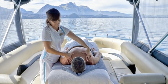 A woman massages the back of a man lying in a boat in the middle of the lake