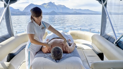 Massage sur le lac Une femme masse le dos d'un homme allongé dans un bateau au milieu du lac.