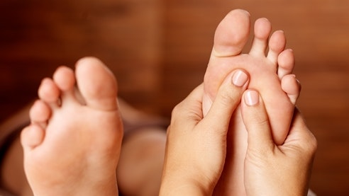 Massage réflexe des zones plantaires Quelqu'un masse la plante d'un pied avec les deux mains.