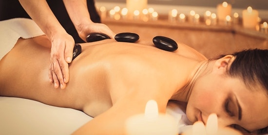 Warm stones are placed on the back of a woman lying on her stomach