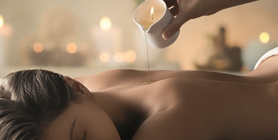 Someone pours liquid oil from a candle onto a woman's back