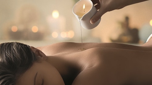 Massage à l'huile de bougie Quelqu'un verse de l'huile liquide d'une bougie sur le dos d'une femme.