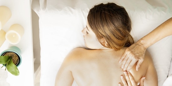 Bird's eye view: Woman lying on a massage table and being massaged by two hands