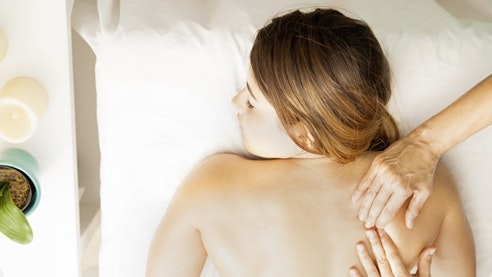 Massage Lomi-Lomi Vue aérienne : femme allongée sur une table de massage et massée par deux mains