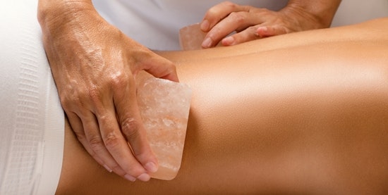 Someone massaging a woman's back with salt stones