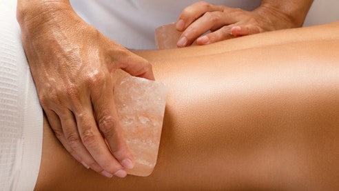 Massage aux pierres de sel Alpienne Quelqu'un masse le dos d'une femme avec des pierres de sel