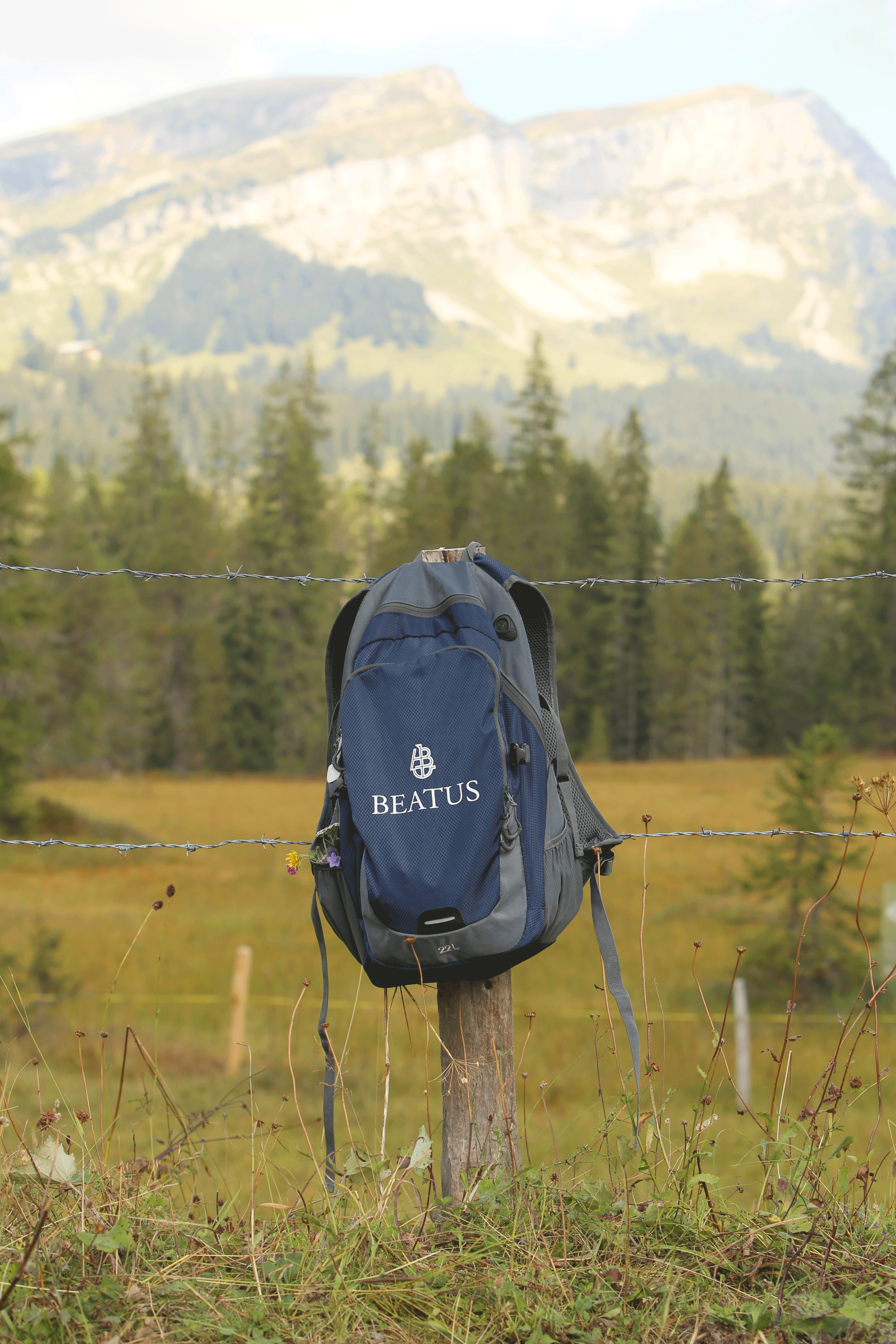 Rucksack hängt auf Zaun, dahinter Berglandschaft