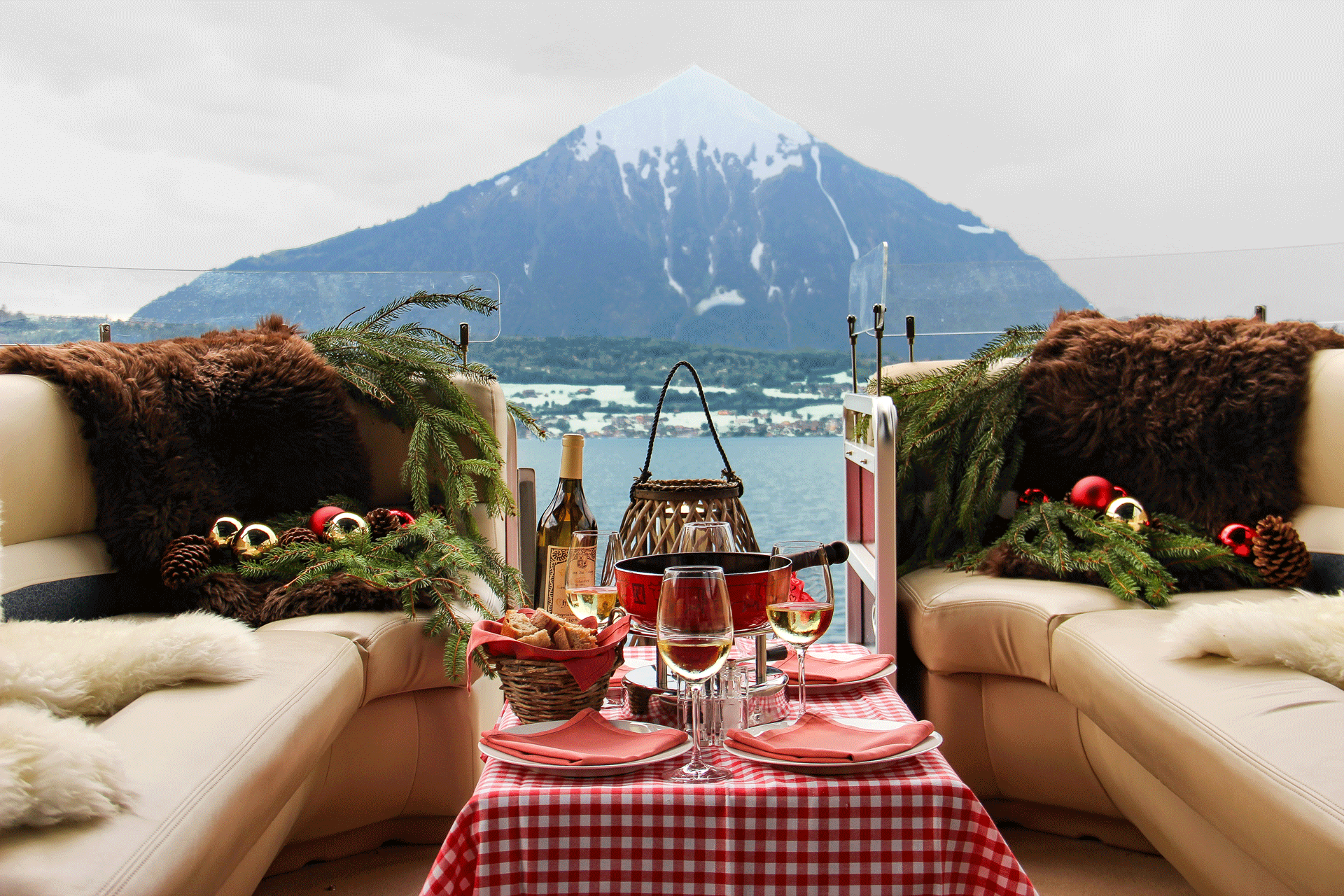An open boat with leatherette benches and Christmas decorations, fondue on a table, a mountain in the back