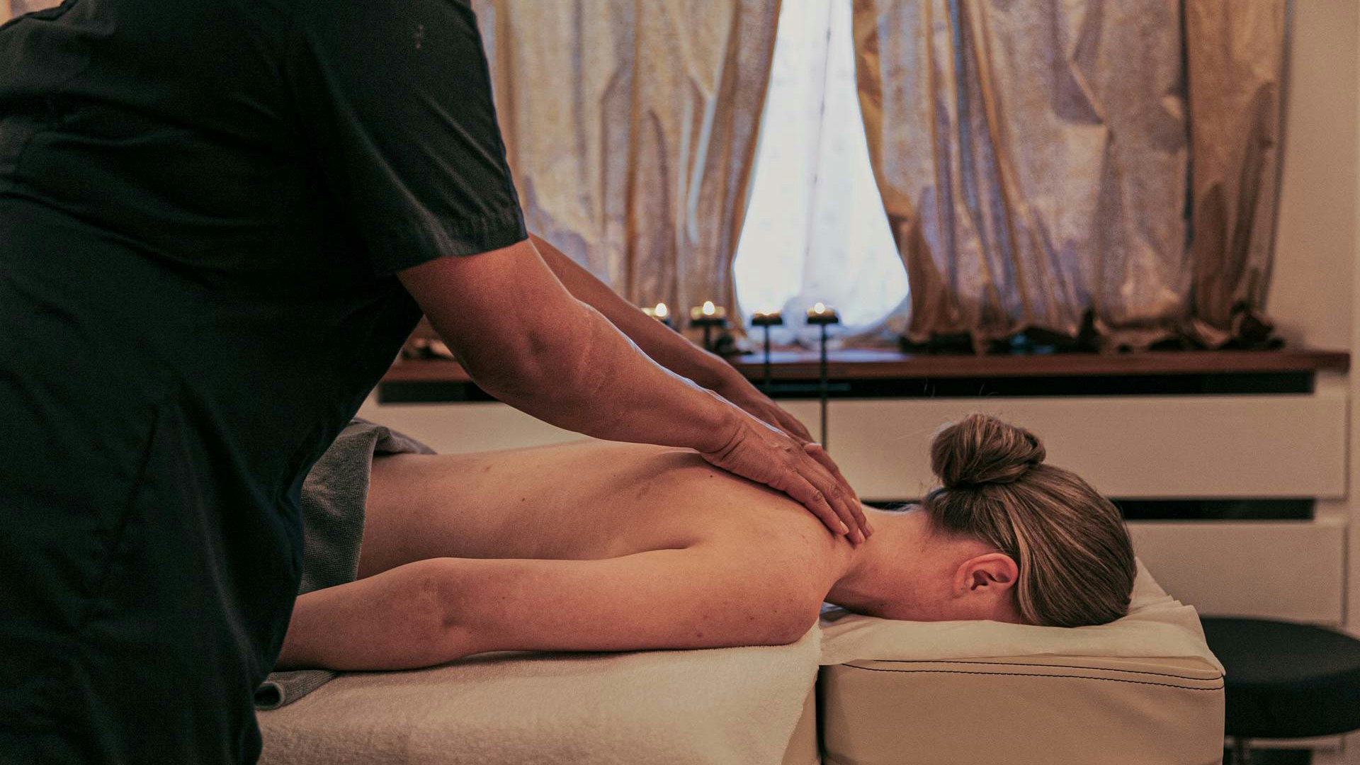 Pantai Luar massage Une femme est allongée sur le ventre sur une table de massage et se fait masser les épaules par une autre femme.