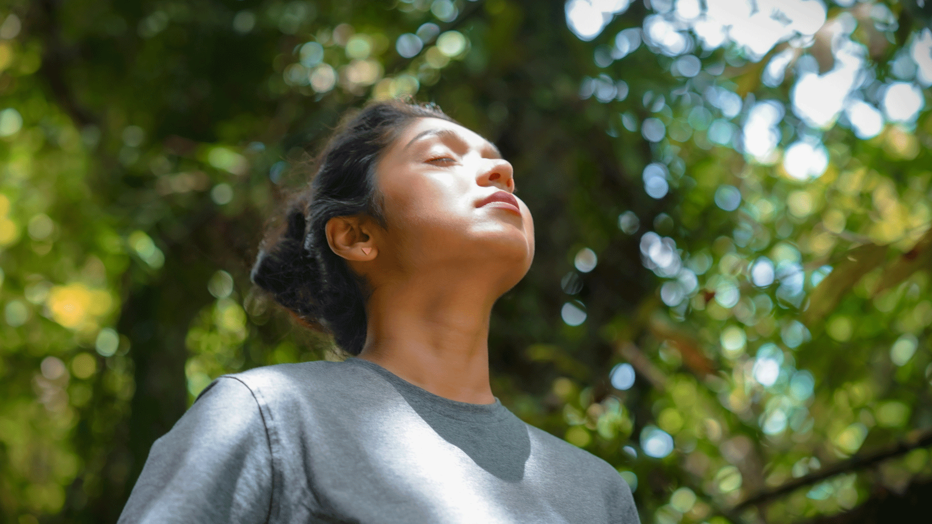 Retraite de yoga Femme debout dans la forêt, laissant le soleil briller sur son visage