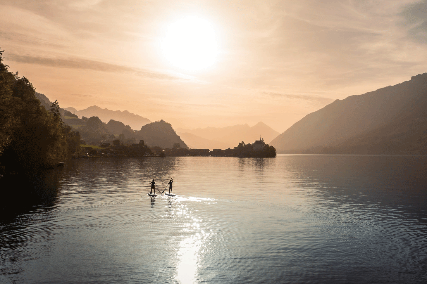 Deux personnes avec un SUP sur le lac au coucher du soleil
