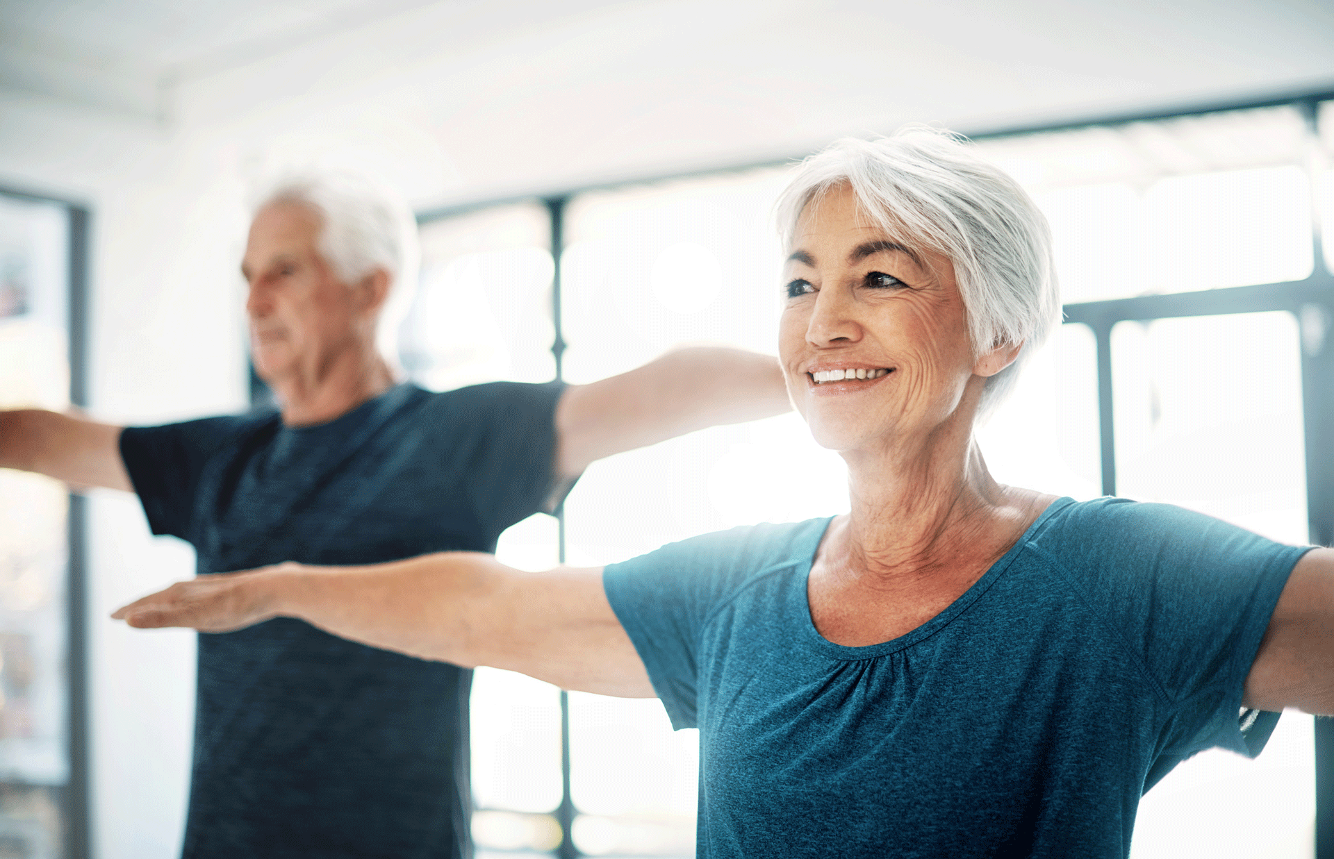 A woman and a man with white hair stretch their arms out to the side