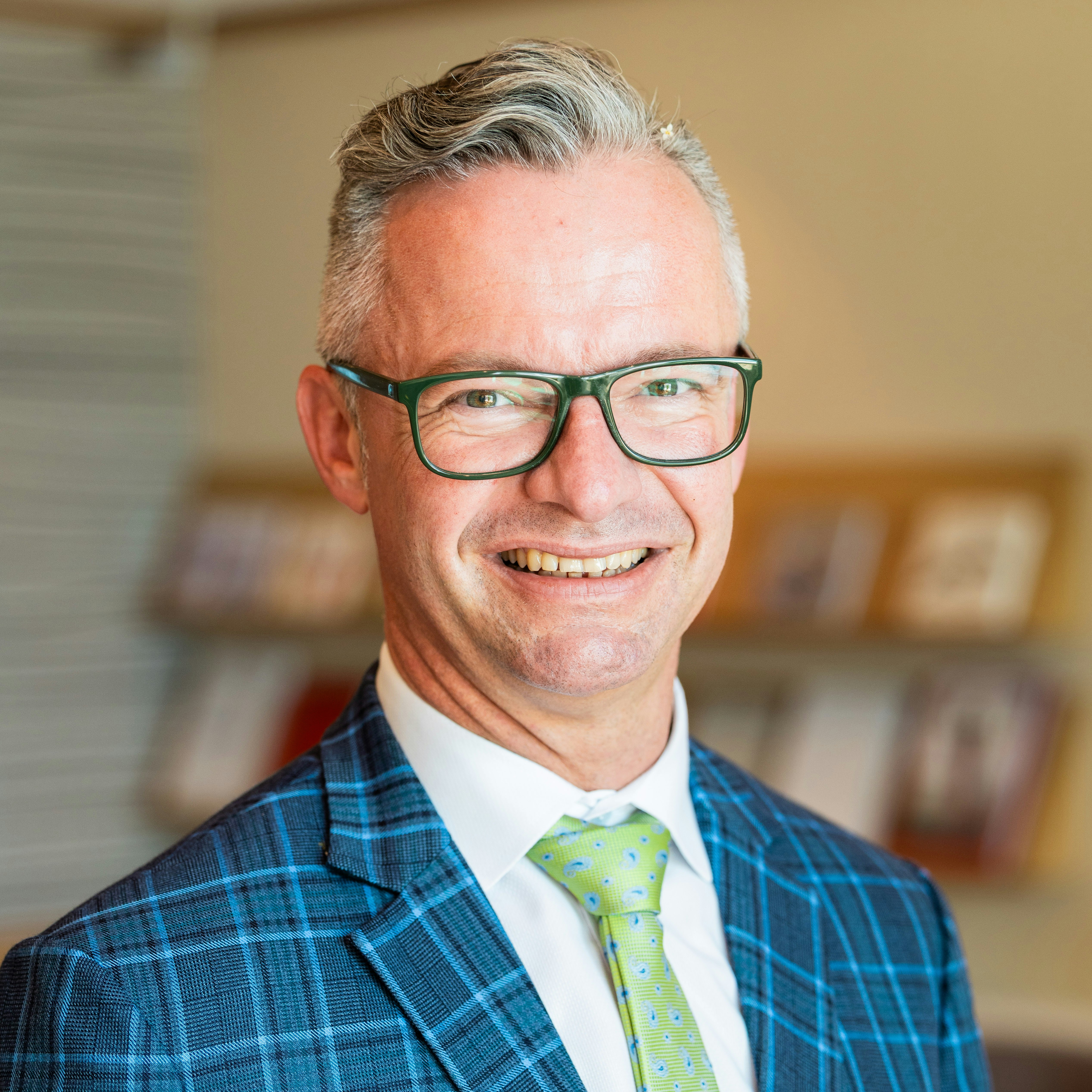 Holger Rauwolf, Maître d'hôtel im Hotel BEATUS Mann mit weissem Hemd und kariertem Sakko, im Hintergrund unscharf ein Regal mit Magazinen