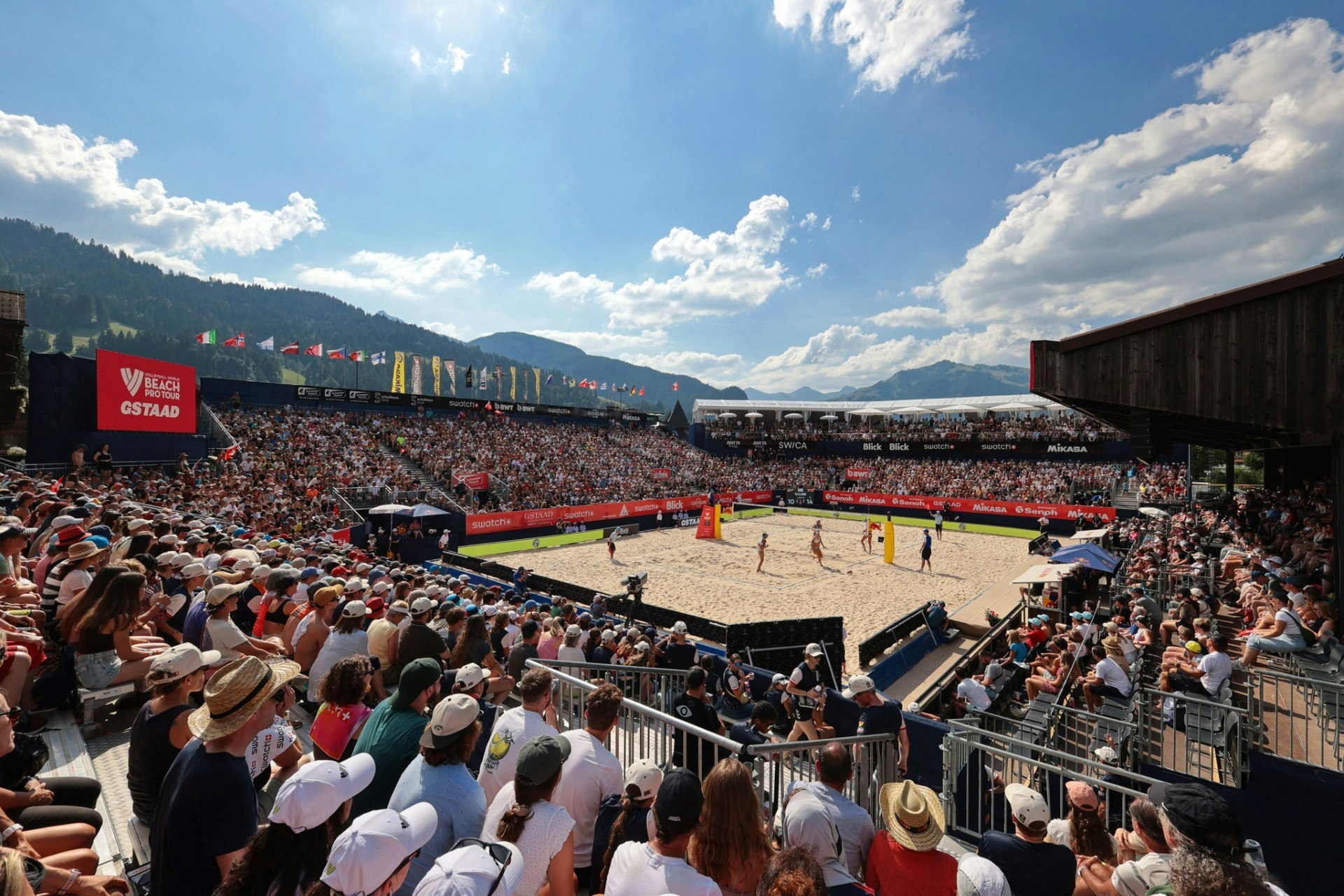 Ein vollbesetztes Stadion mit einem Volleyballfeld in der Mitte, begeisterte Zuschauer verfolgen das Volleyballspiel.