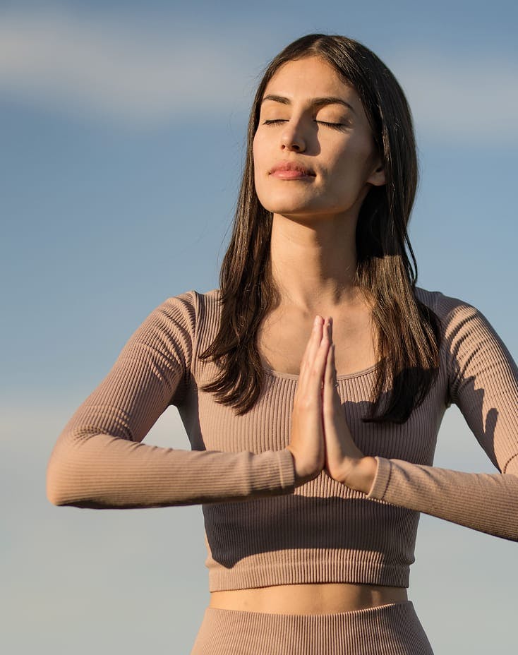 woman with palms together and eyes closed