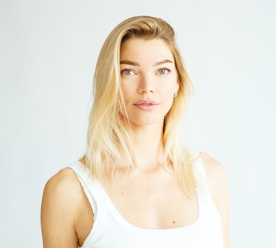 woman with blonde hair looking forward wearing a white tank top