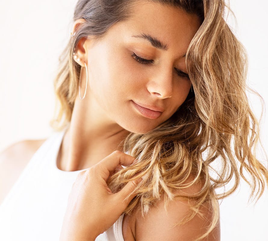 woman looking over her shoulder and touching the ends of her hair
