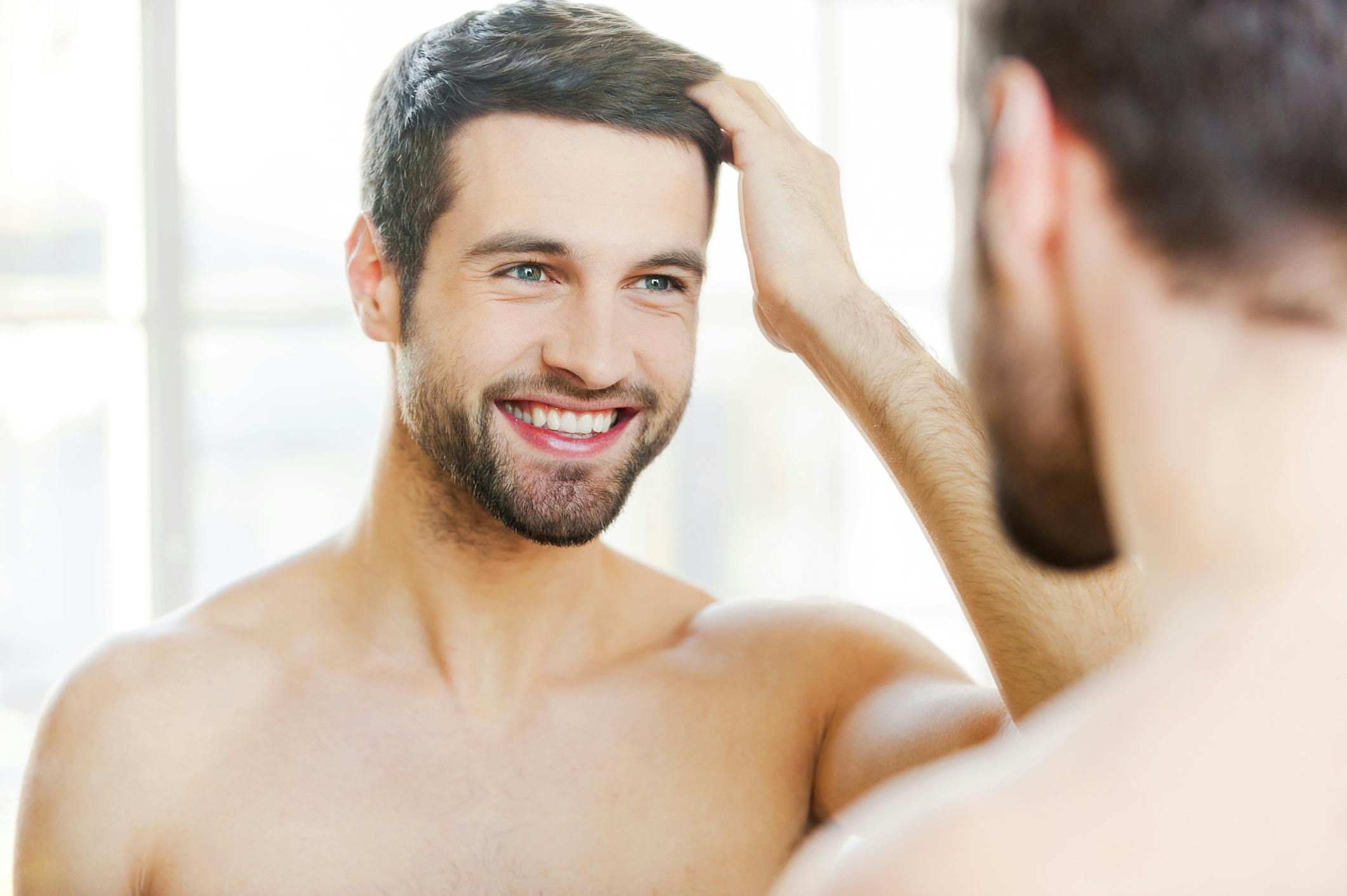 Man looking at his hair in the mirror