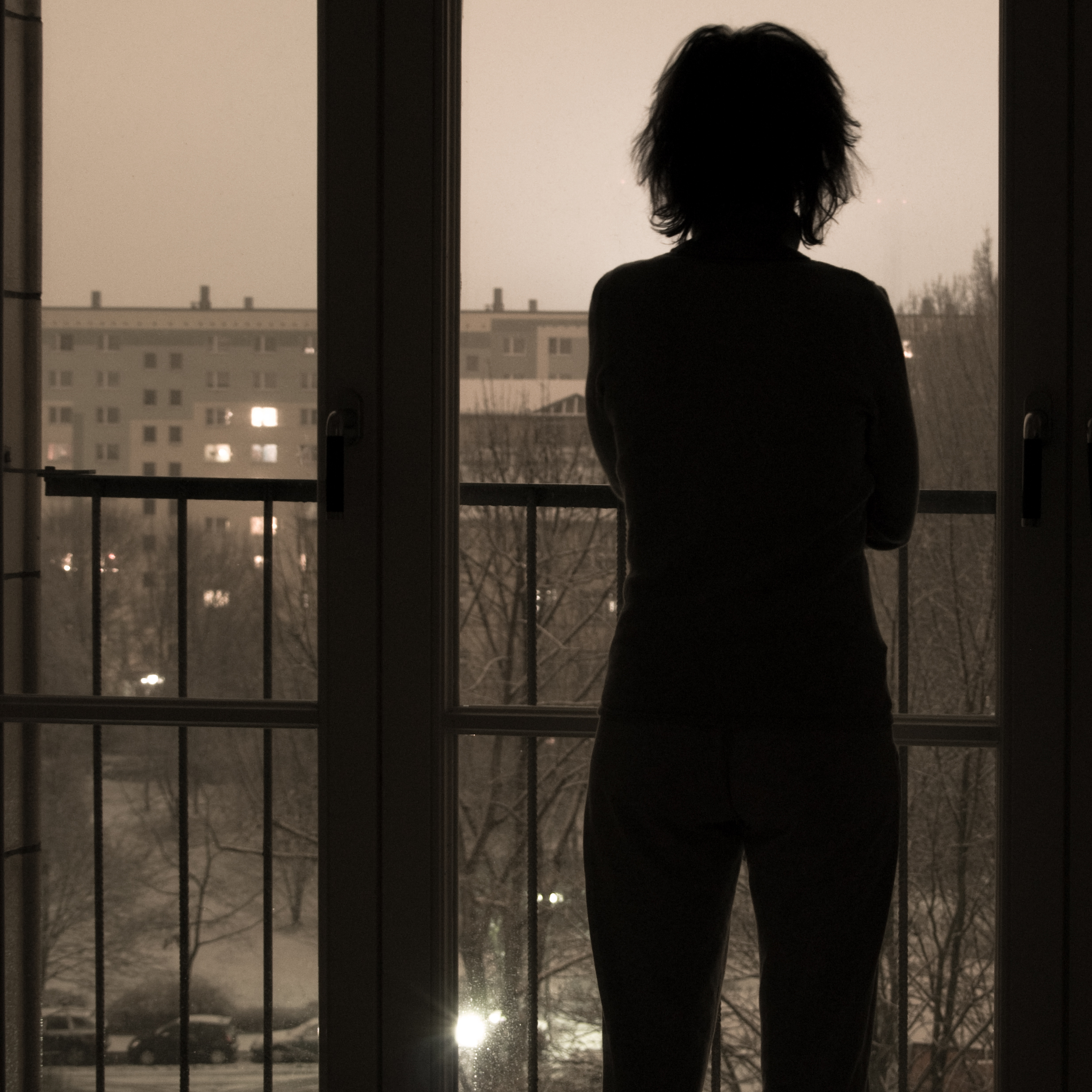 Silhouette of a woman looking out her window